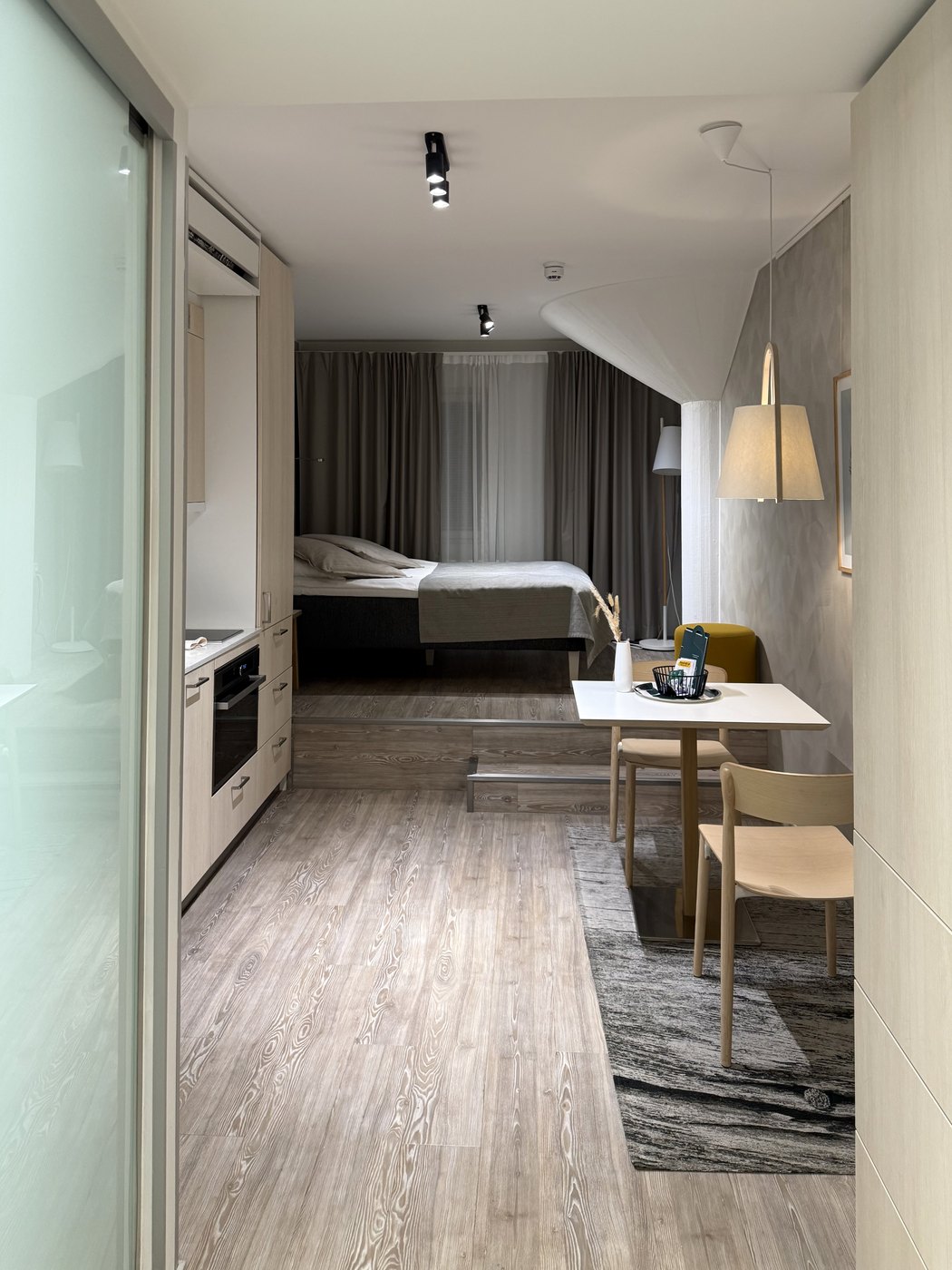 Jasny pokój hotelowy z łóżkiem i stołem, widziany od wejścia po przyjeździe